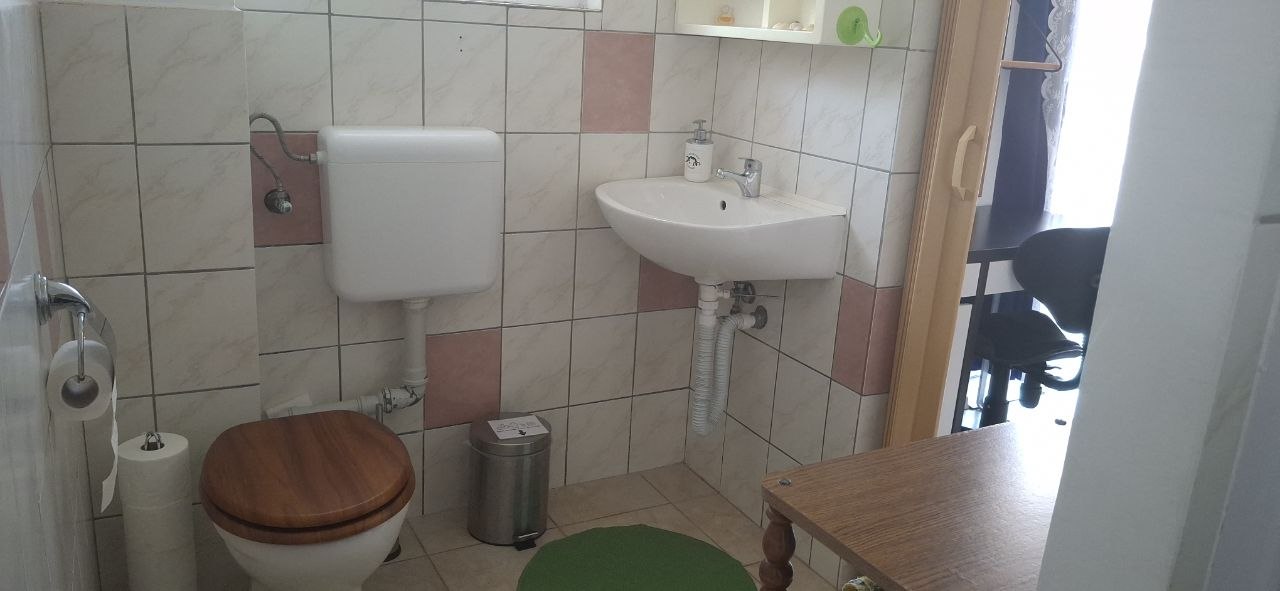Földszinti WC mosdóval és csempézett falakkal
