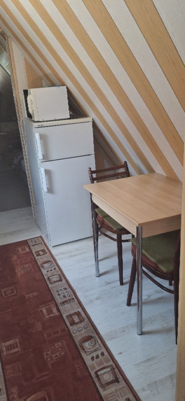 Kétszemélyes asztal a hűtő mellett a csíkos tetőtéri étkezőben
